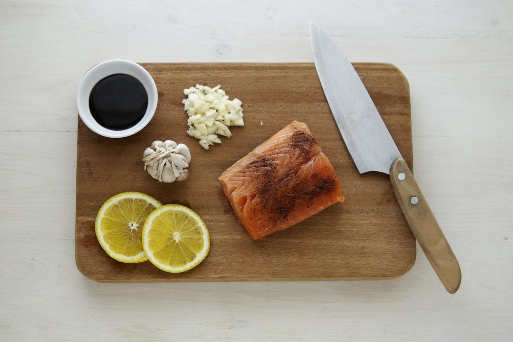 gray knife and orange flesh meat on wooden chopping board
